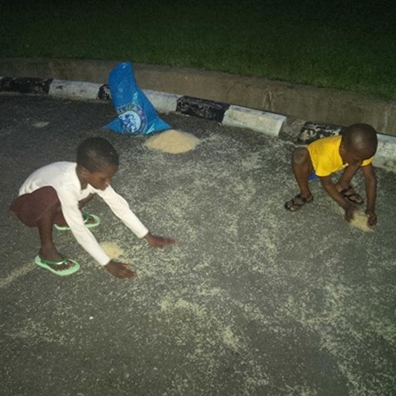 children packing spilled rice from the ground